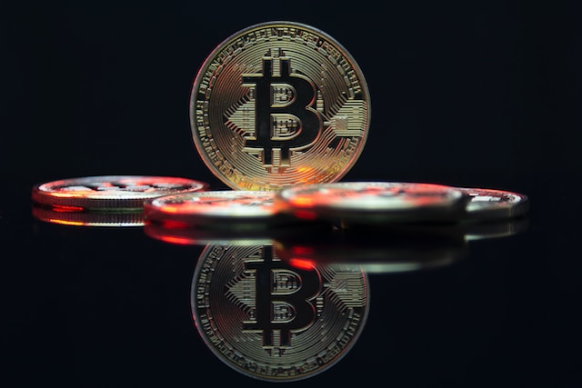 Pile of Bitcoin with one standing up and its reflection showing on the smooth surface